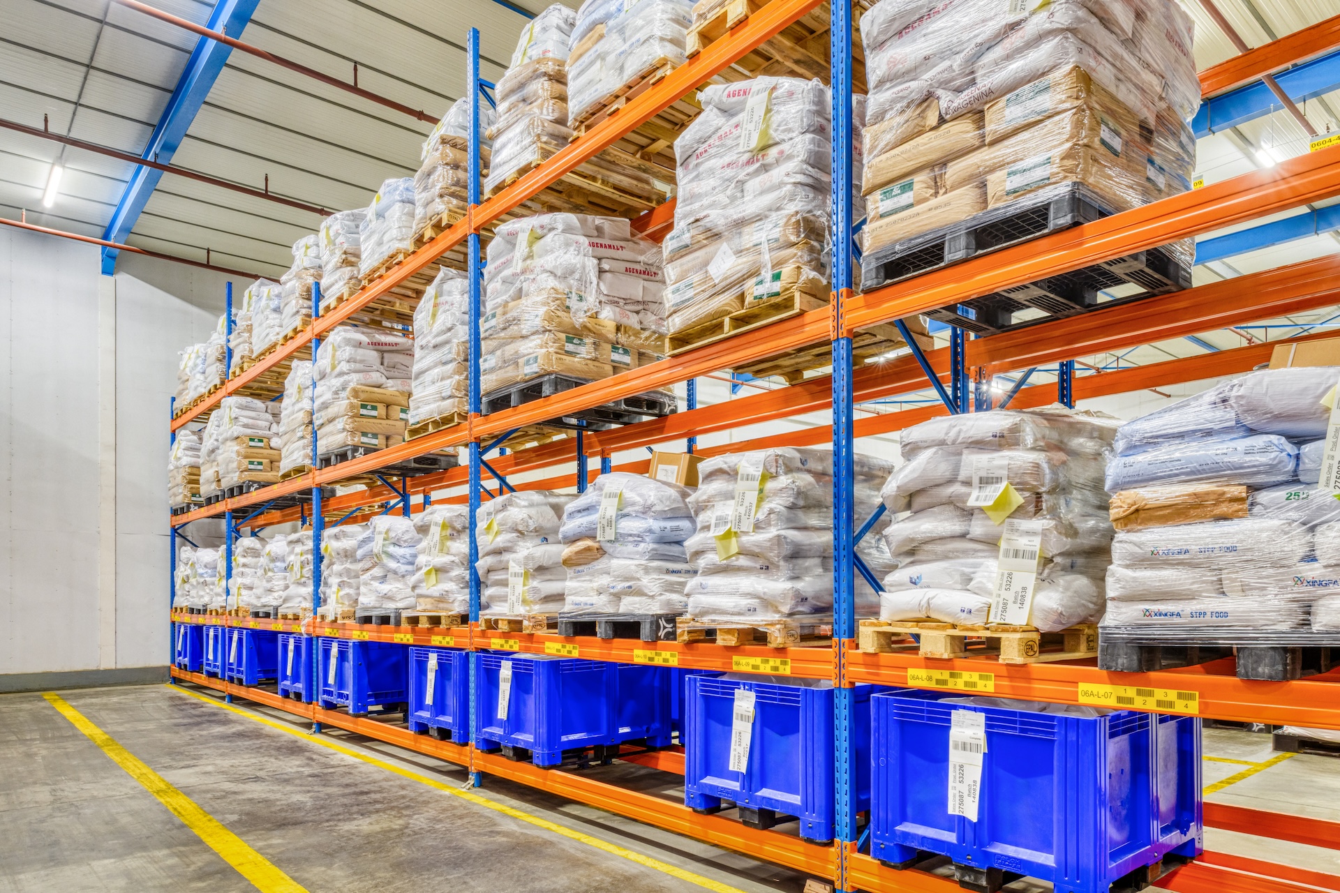 Magazijnstellingen met pallets en blauwe bakken.