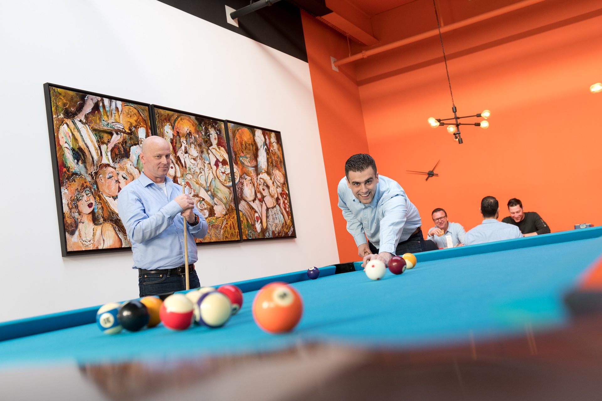 Collega’s spelen pool in kantoorruimte.