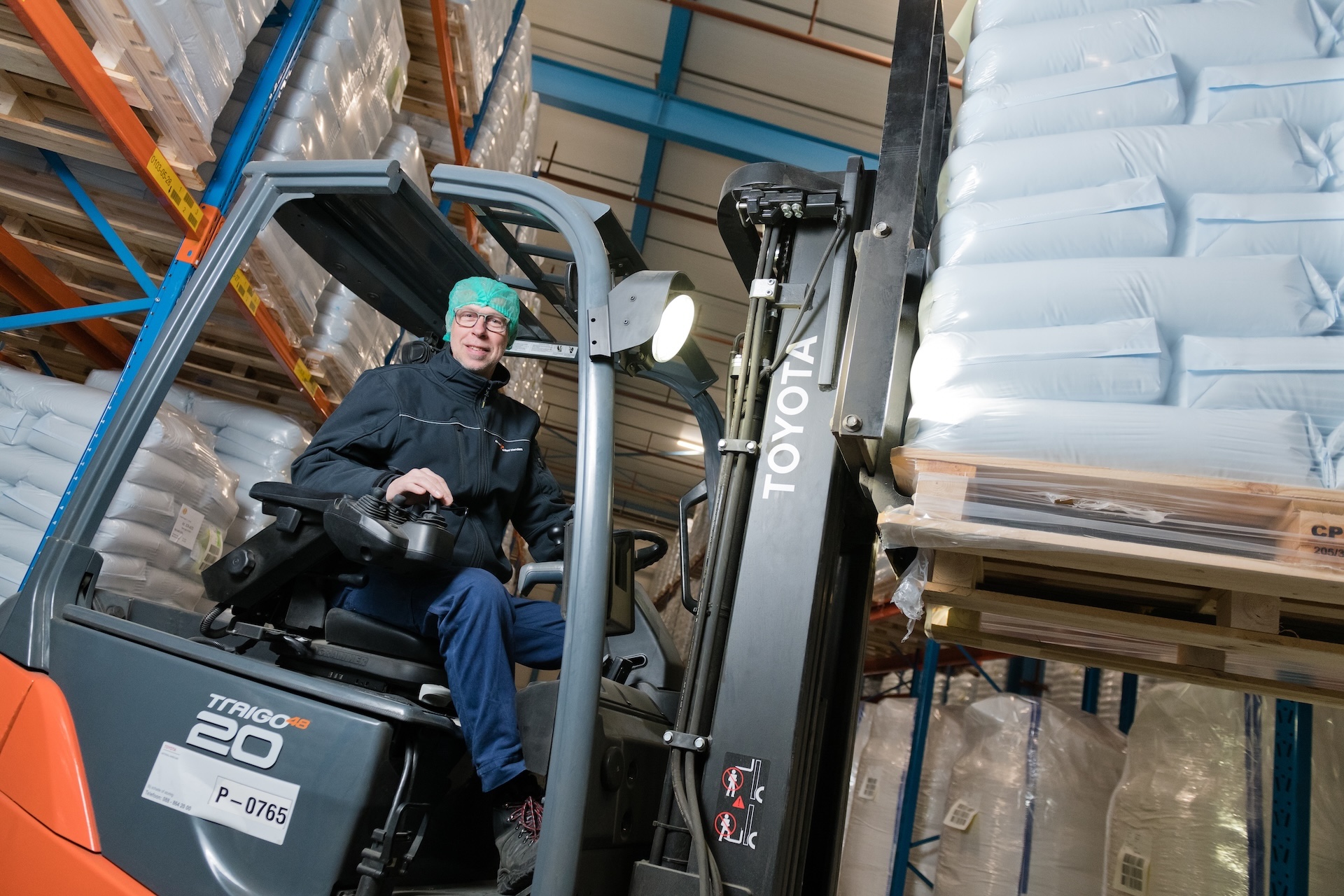 Heftruckchauffeur verplaatst pallets met zakken in magazijn.