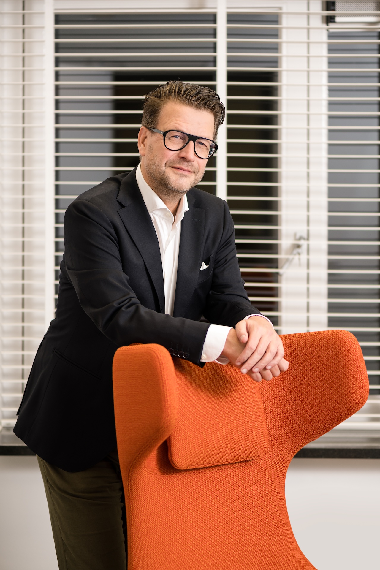 Portret van manager leunend op oranje stoel.