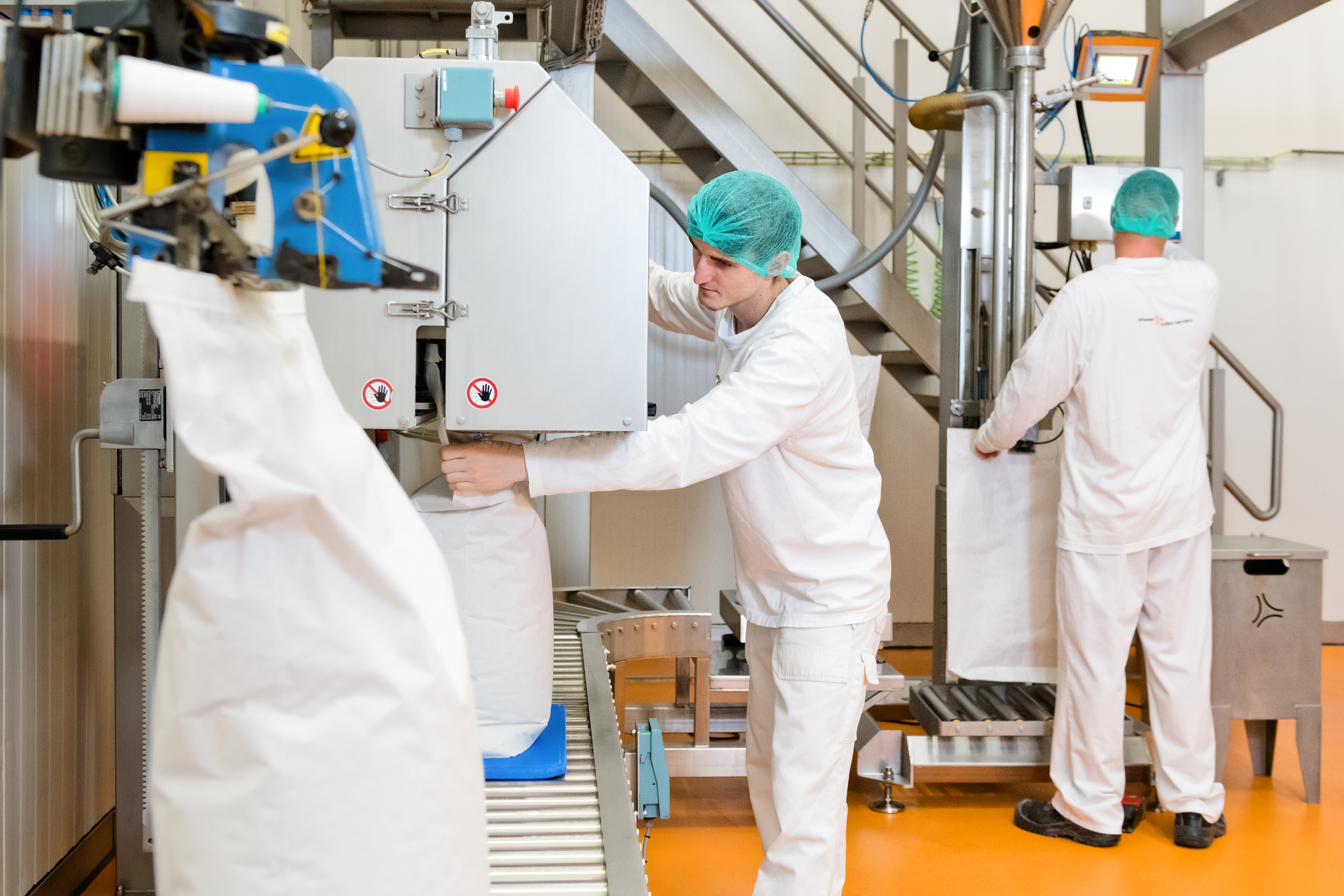 Twee operators bedienen grote productiemachine.