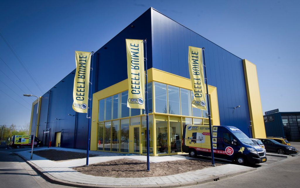 vlaggen met slogan 'geeft ruimte' en verhuisbus voor allsafe vestiging