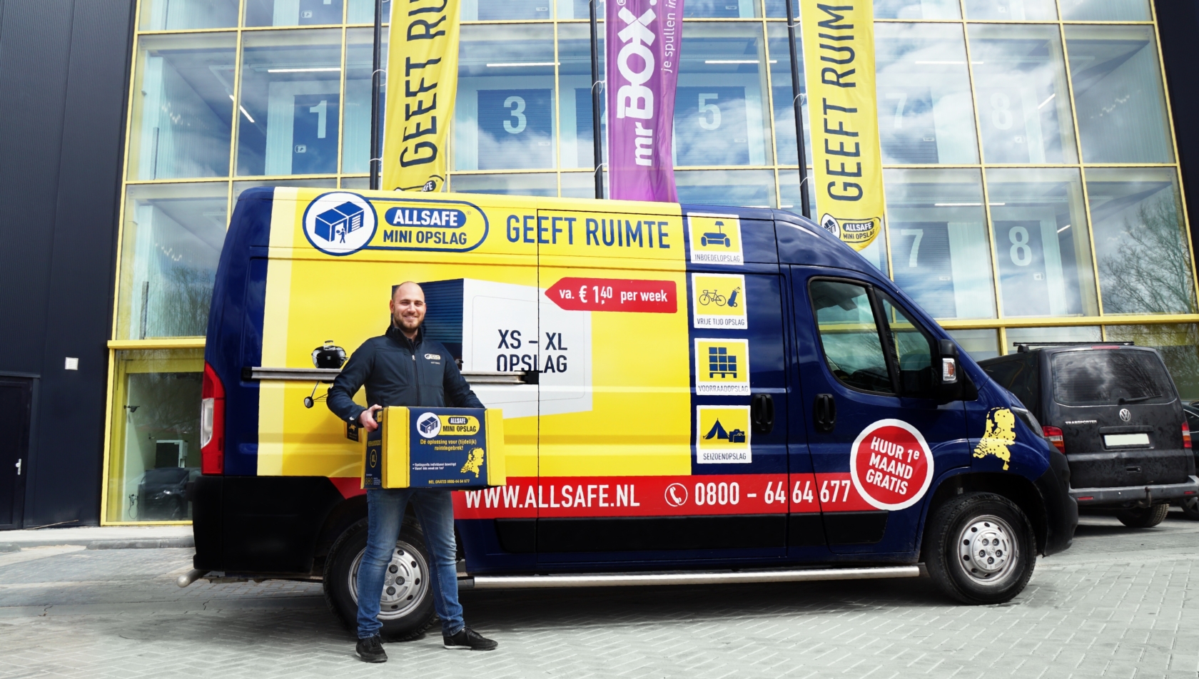 medewerker allsafe poserend met verhuisbox voor verhuisbus