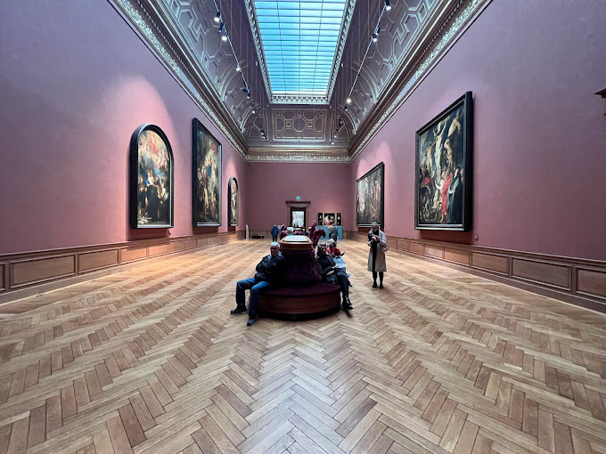 Pink gallery hall with classical paintings and skylights