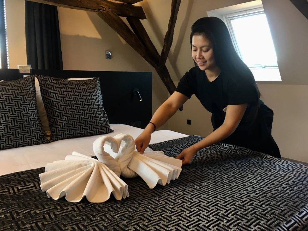 Een medewerker legt een handdoekzwaan op het bed van een gast