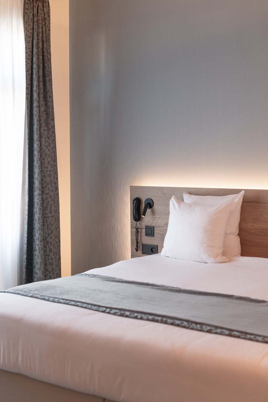 Hotelkamer met houten hoofdeinde en witte kussens