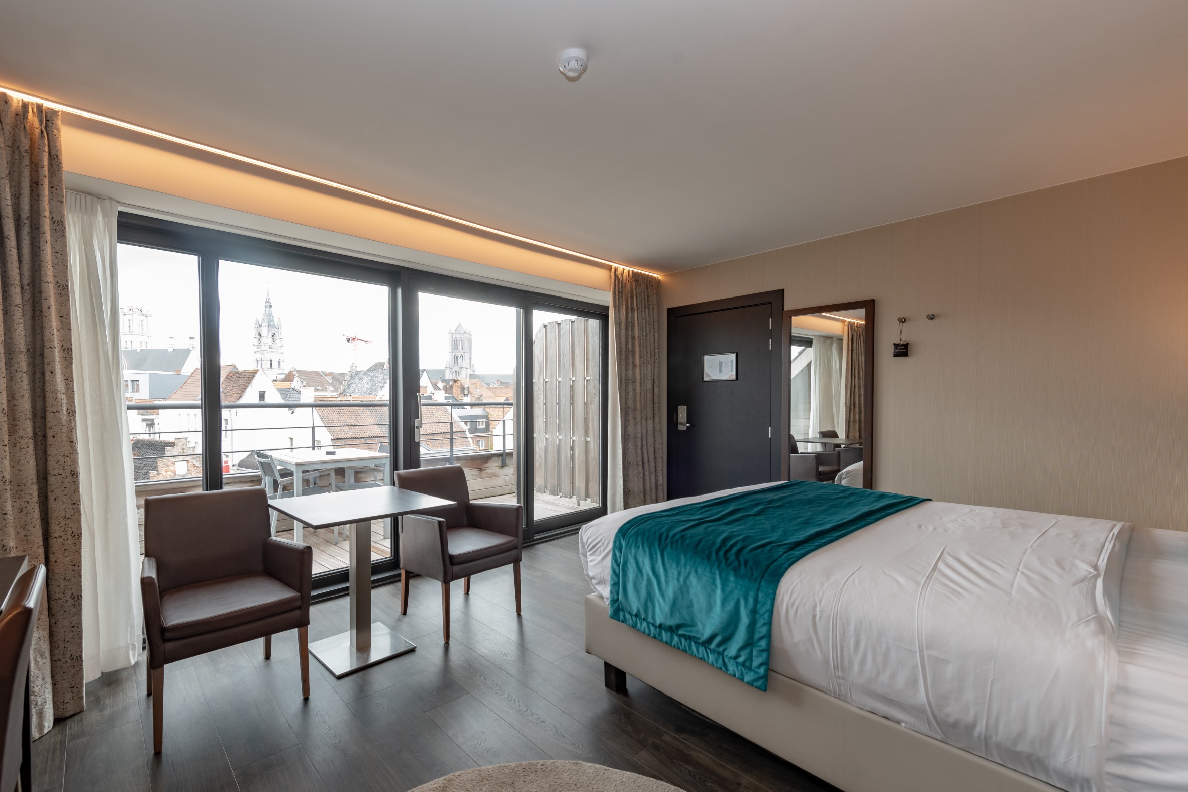 Slaapkamer met balkon en zicht op de historische daken van Gent