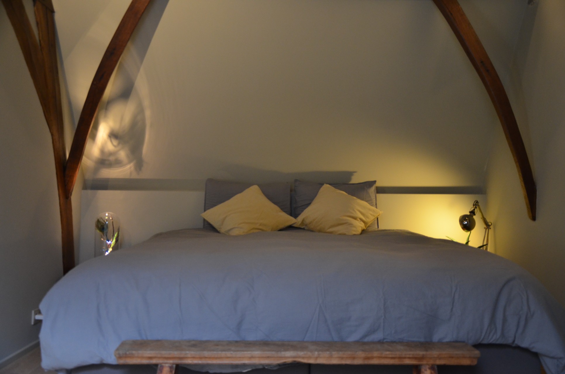 Kamer Het Atelier met gebogen houten balken boven het bed