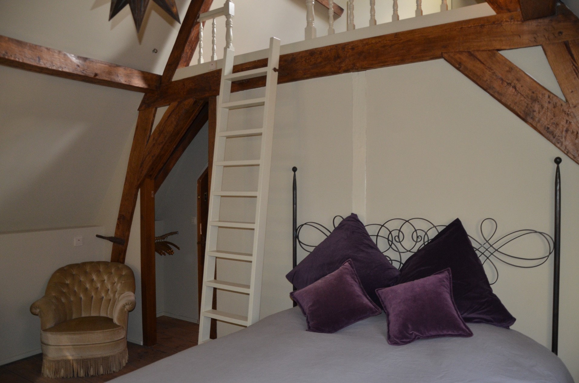 Zolderkamer De Mezzanine met houten balken en het slaapgedeelte op de mezzanine