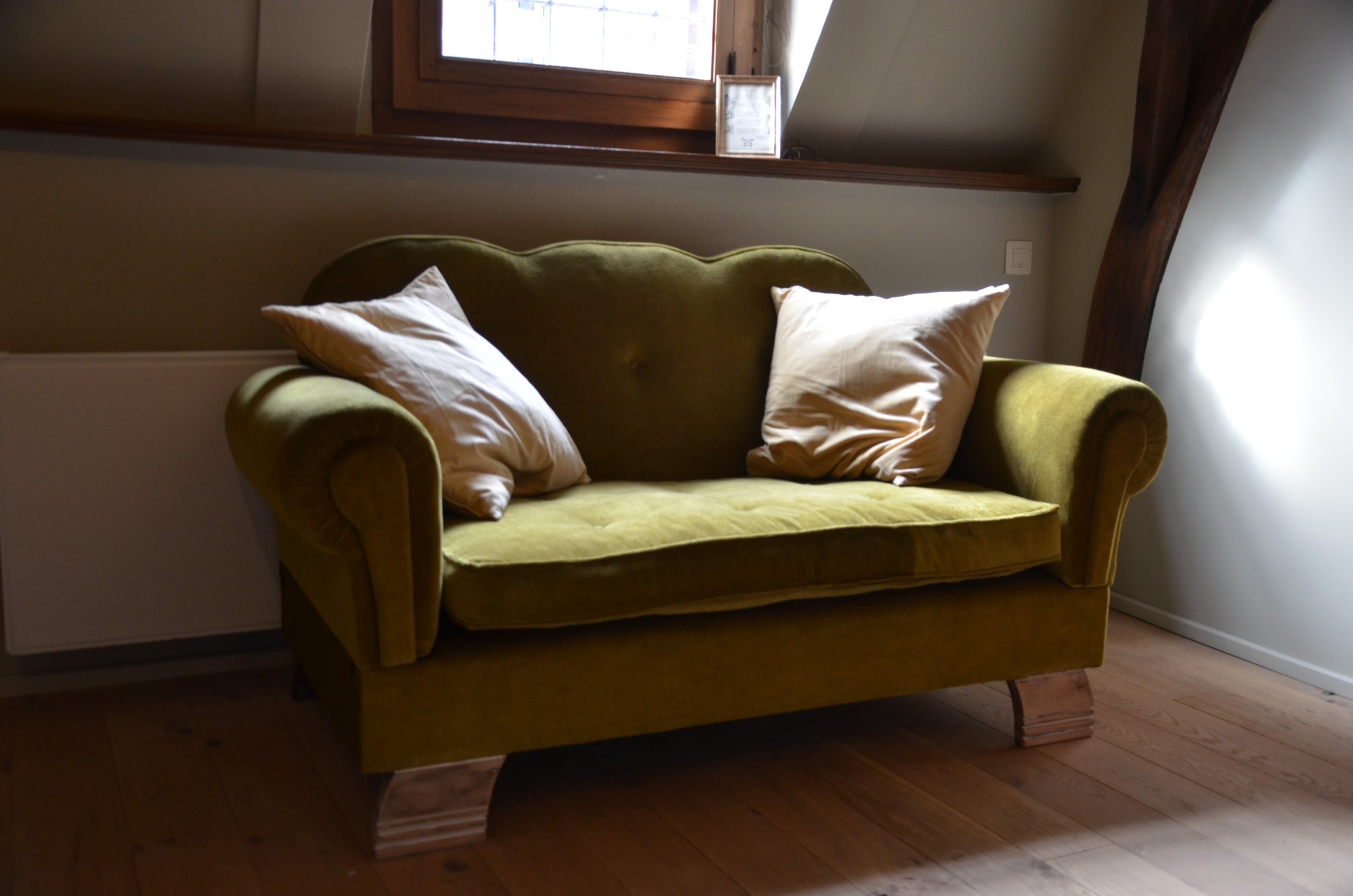 De zithoek met witte kussens op de olijfgroene sofa