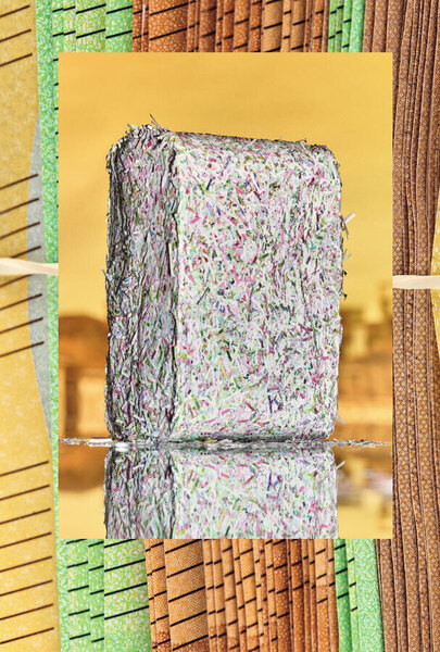 Ein quaderförmiger Block aus buntem, zerkleinertem Papier steht auf einer spiegelnden Fläche. Das Papier besteht aus vielen kleinen, farbigen Schnipseln. Der Block wird von einem farbenfrohen, geometrischen Hintergrund umrahmt.