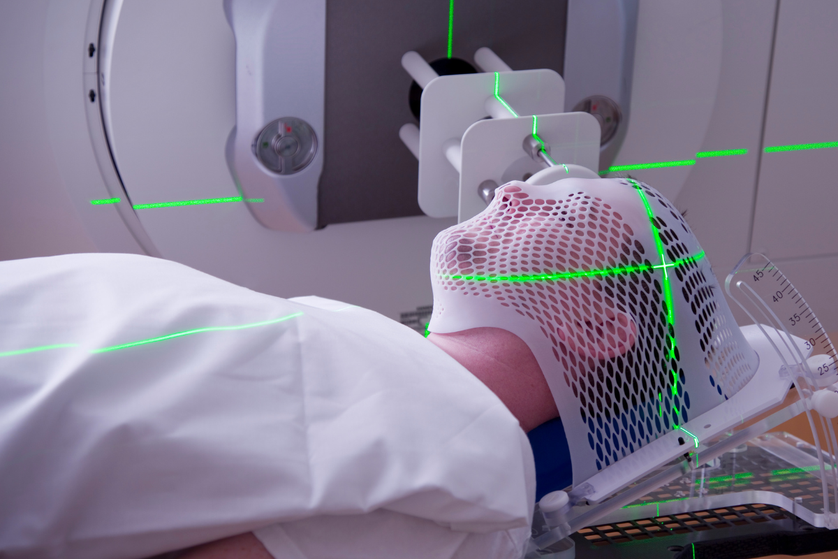 Man lying on table being treated with radiation therapy for his head.