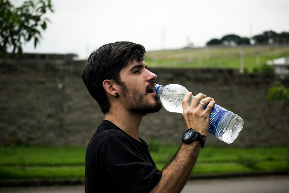Man standing outside drinking from a water bottle.