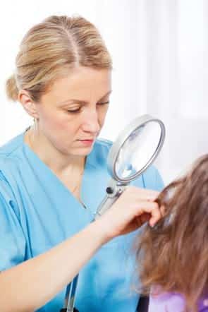 nurse inspecting child's hair for lice
