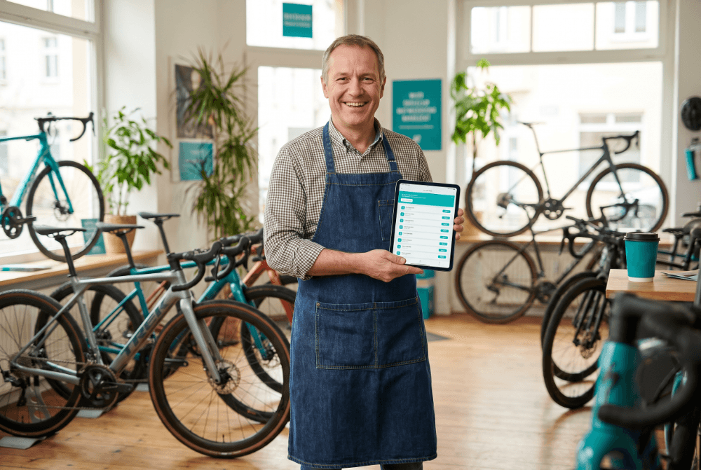 Freundlicher Fahrradhändler im Laden mit Tablet