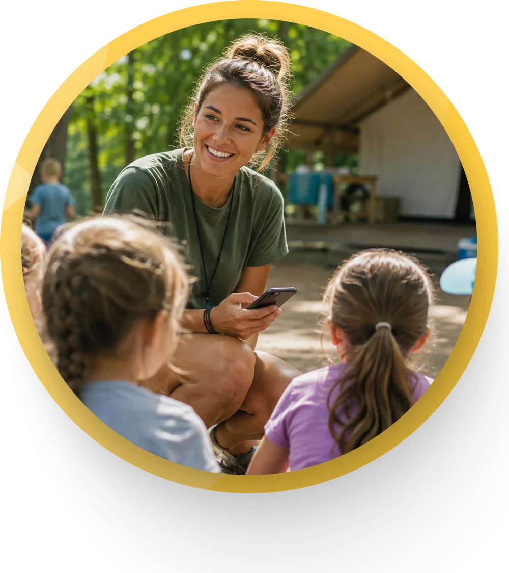 Counselor with campers outdoors, phone in hand