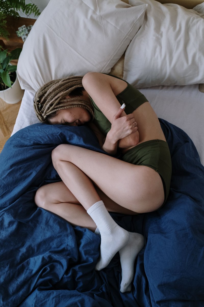 Woman Suffering from a Stomach Pain Lying Down on Bed · Free Stock Photo