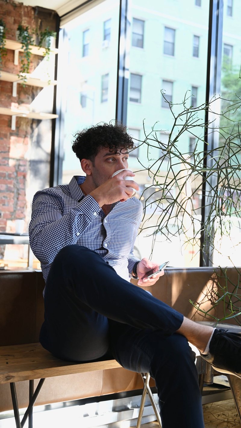A Man Drinking Coffee while Holding a Cellphone