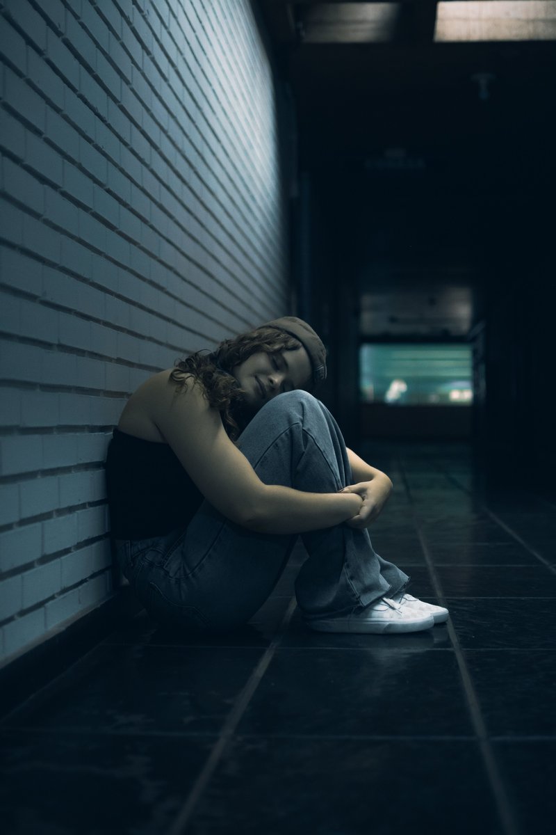 Woman Reflecting Alone in a Dark Hallway · Free Stock Photo