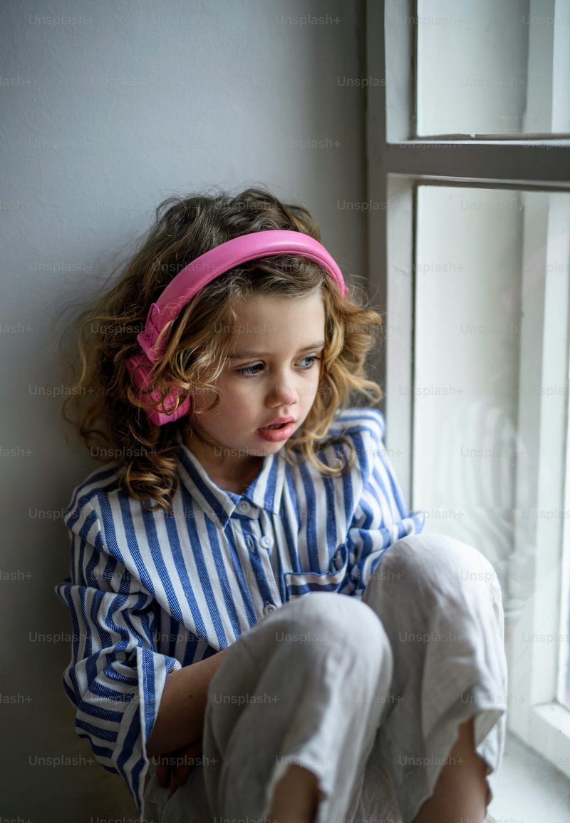 Portrait of sad small girl with headphones indoors at home, sitting on window sill. photo – Girl Image on Unsplash