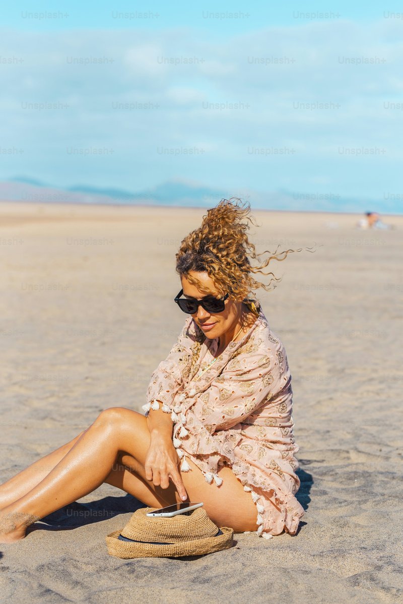 Female tourist relax under the sun in summer holiday vacation day at the beach using mobile phone. Attractive adult woman enjoy connection outdoors. Free solo single lady people in tourism activity photo –