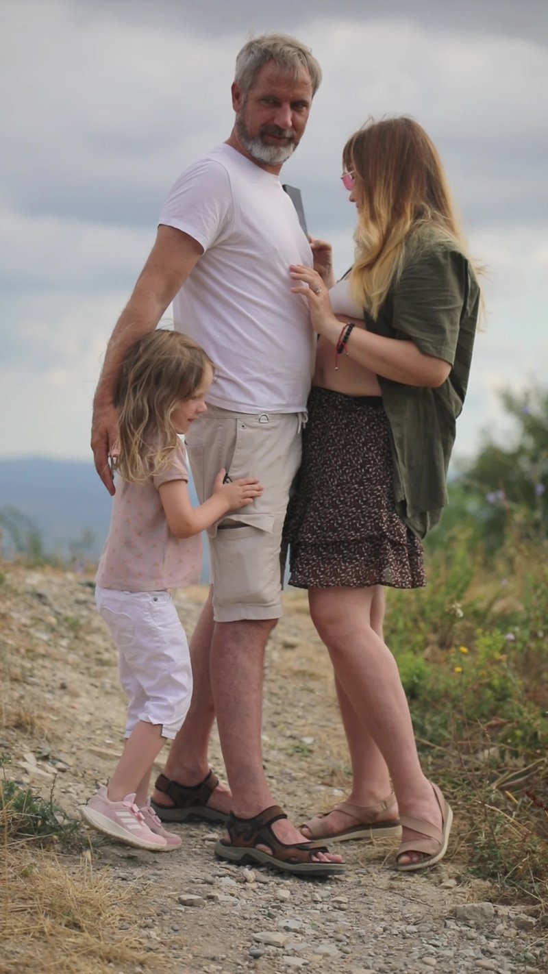 A family standing on a dirt road with a sign that says, the best way to raise a child