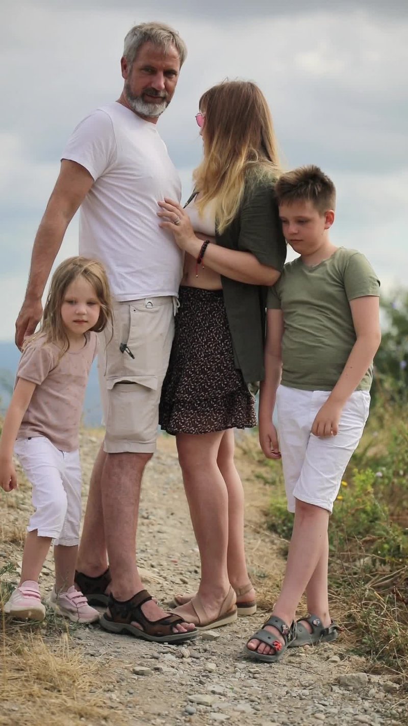 A family is standing on a dirt road