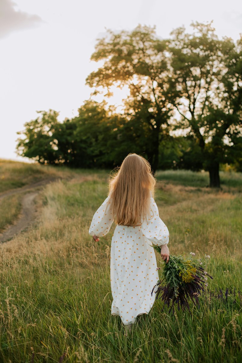 A little girl in a white dress walking through a field - Free Photo on Unsplash