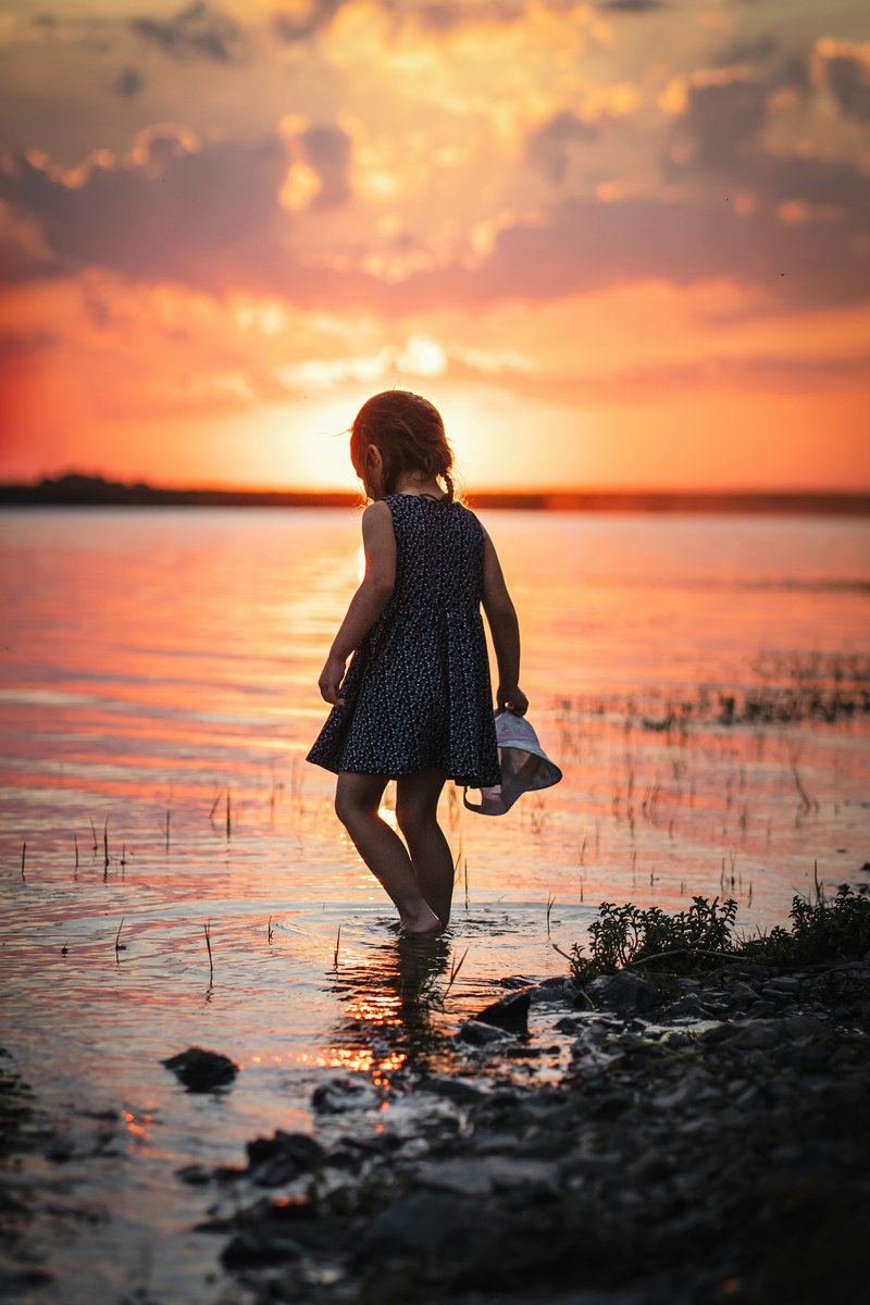 A little girl standing in the water at sunset - Free Photo on Unsplash