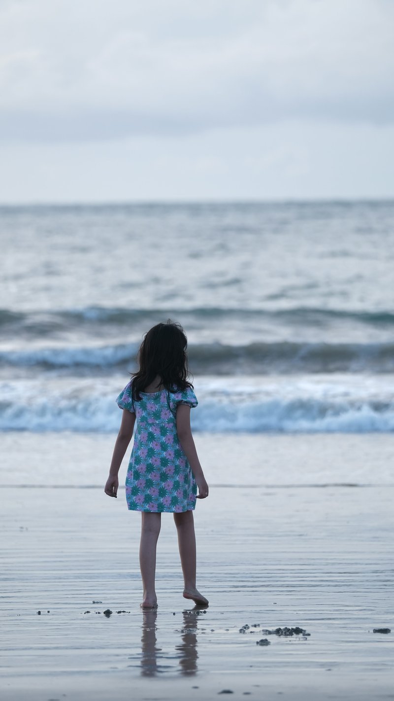 A little girl standing on top of a beach next to the ocean - Free Photo on Unsplash