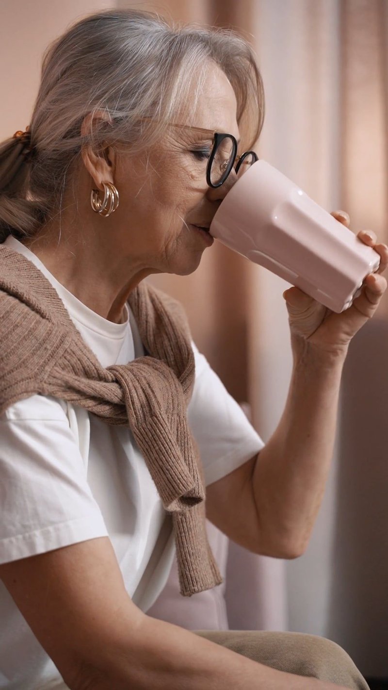 Elderly Woman Drinking from a Cup