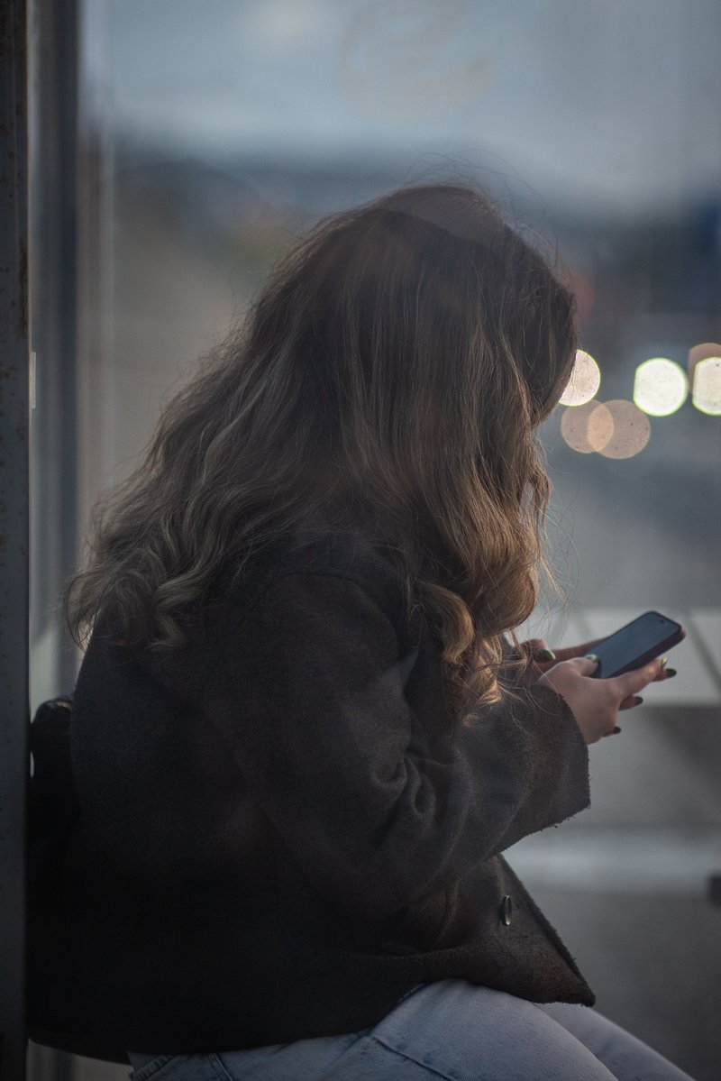 Young Woman Using Smartphone at Bus Stop in Eskişehir · Free Stock Photo