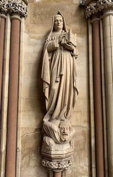 a stone sculpture standing in front of a wall between columns