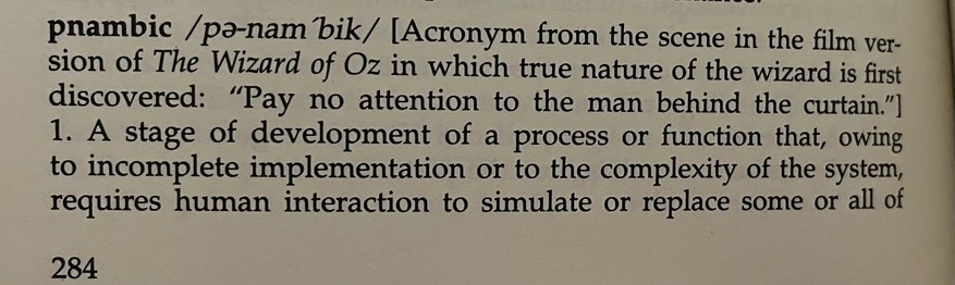 pnambic

[Acronym from the scene in the film version of The Wizard of Oz in which true nature of the wizard is first discovered: "Pay no attention to the man behind the curtain."]

1. A stage of development of a process or function that, owing to incomplete implementation or to the complexity of the system, requires human interaction to simulate or replace some or all of

(continues in the next photo)