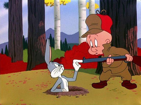 bugs bunny is half out of his hole, sticking his finger into the end of elmer fudd’s shotgun and frowning at him with irritation; elmer fudd is looking at bugs bunny’s finger with surprise