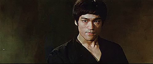 bruce lee invites you into his kill zone with a menacing look on his face