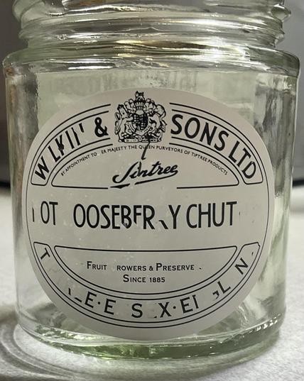 a tiptree hot gooseberry chutney jar with a white label printed in black; about a quarter of the letters are missing or damaged as if they had been carelessly edited out before the label was printed