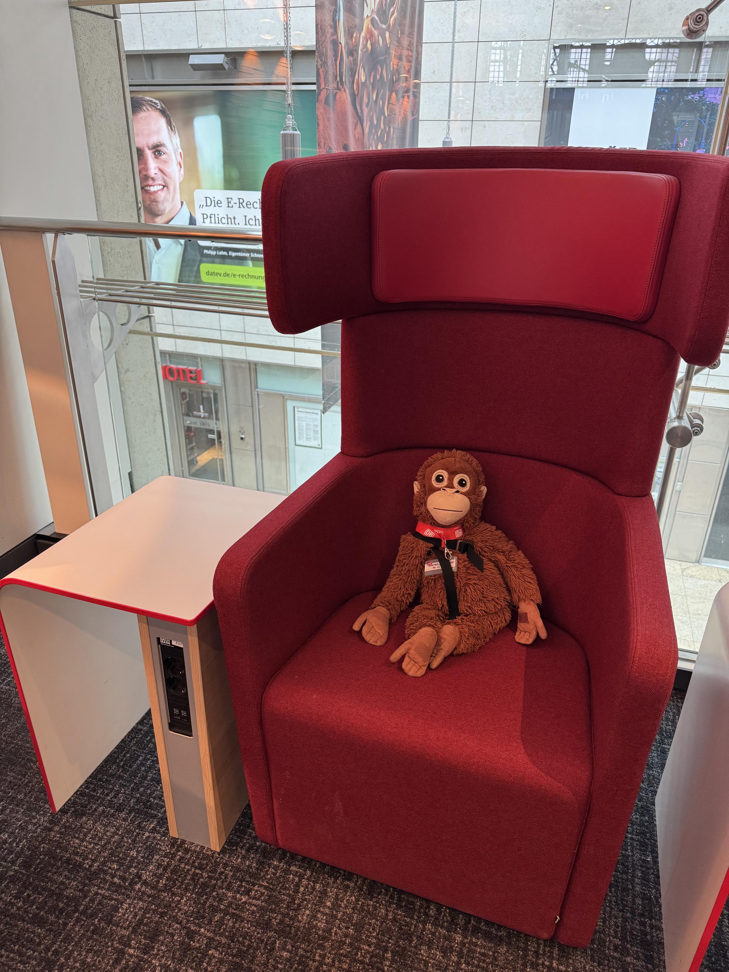 Me sitting on a red DB Lounge high-backed chair. Advertising is visible through the window