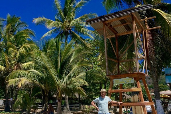 man staat voor strandwacht huisje op palmstrand in costa rica