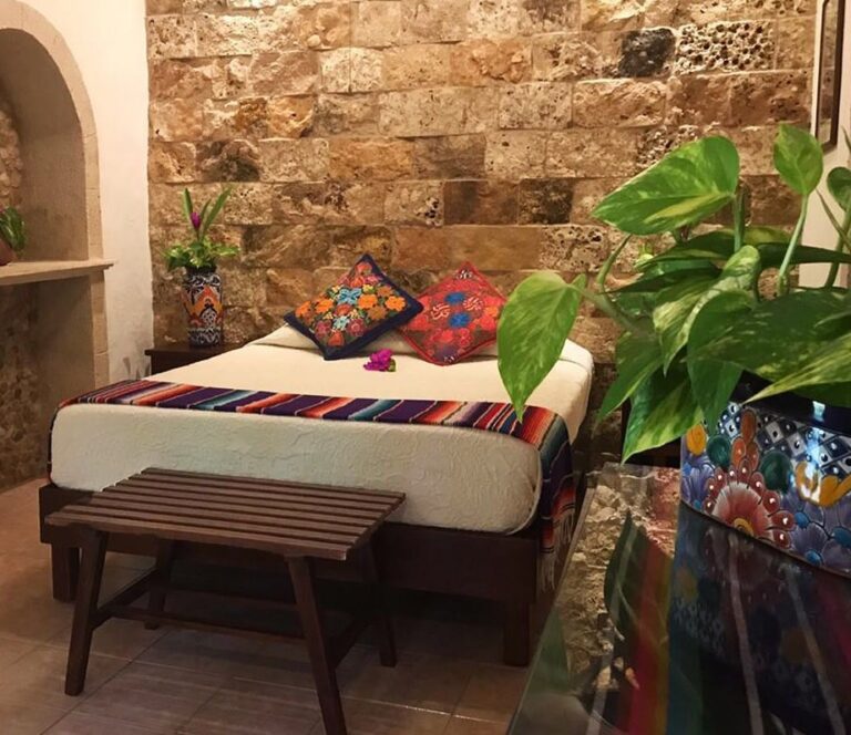 Hotelkamer met opgemaakt bed met planten en mexicaanse look
