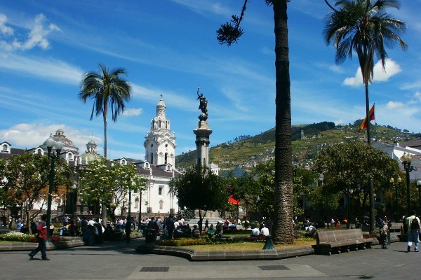 een plein in Quito met een wit historisch gebouw en een beeld in het midden
