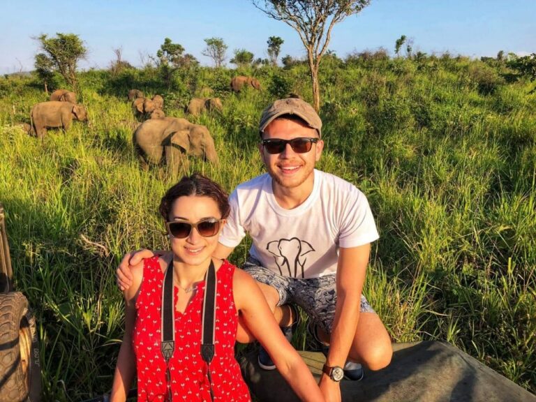 man en vrouw poseren gehurkt in de bush van sri lanka met achter hen olifanten