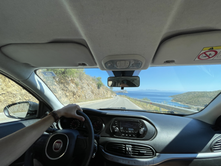 foto vanuit de auto met zicht op de weg en de zee
