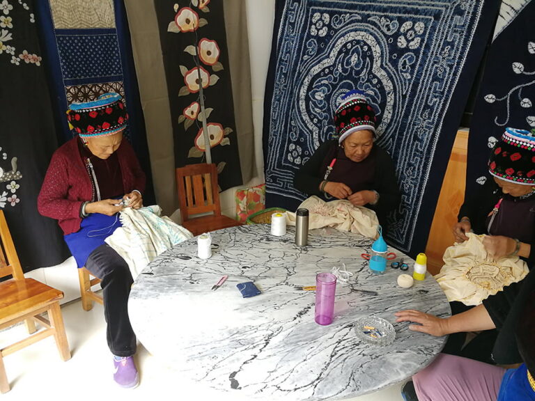 Vrouwen van Bai-etnische minderheid in Zhoucheng Village, Yunnan zijn bezig met traditioneel knoopverven