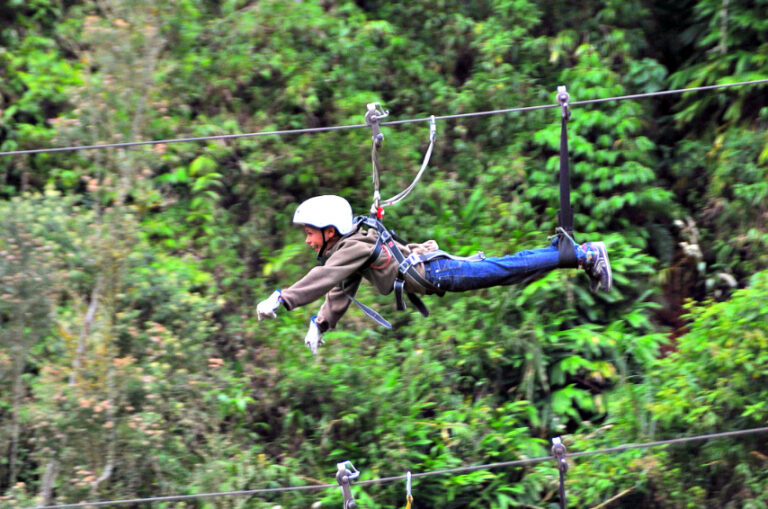 een jongen hangt aan een zipline en vliegt door de boomtoppen