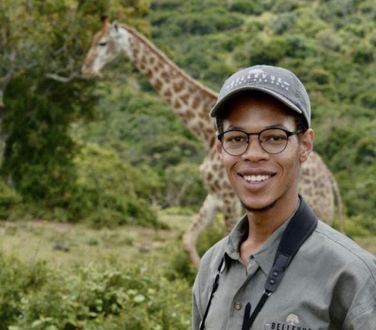 een ranger staat voor een giraffe