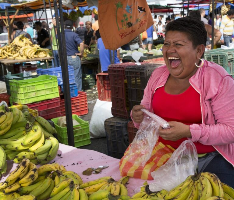 schaterlachende vrouw op markt achter bananen