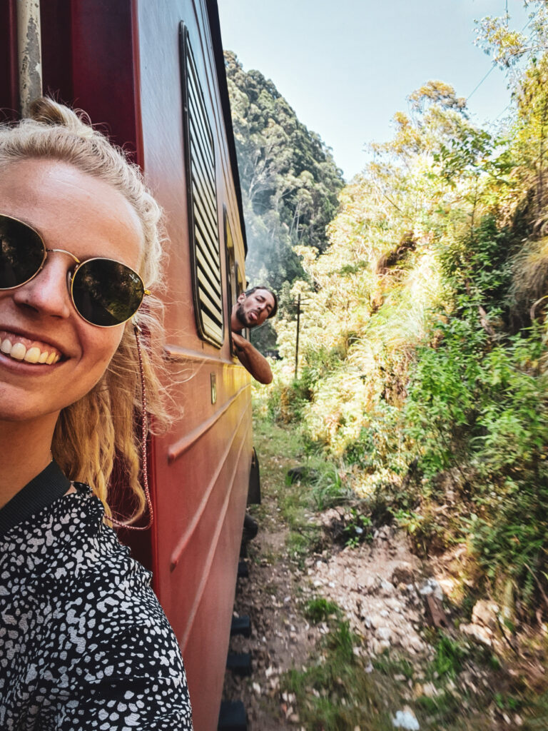 reizigers leunen uit trein tijdens rit door theeplantages Sri Lanka