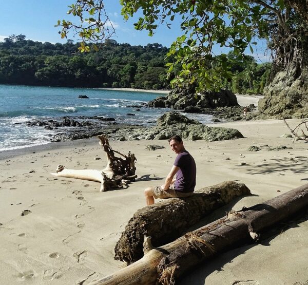 reiziger rust op gevallen boomstand aan strand Manuel Antonio
