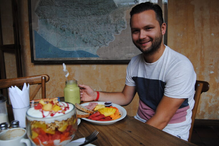 lachende reiziger aan fruitontbijt en smoothie